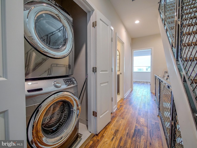 laundry room featuring hardwood / wood-style flooring and stacked washer and dryer