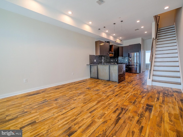 kitchen with decorative light fixtures, tasteful backsplash, sink, stainless steel fridge, and light wood-type flooring