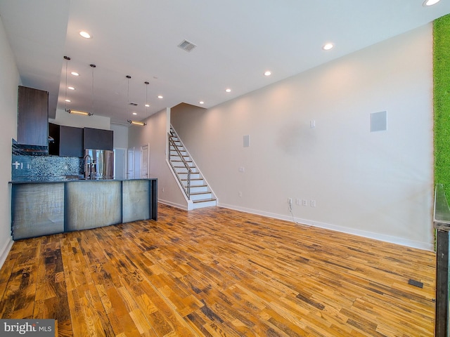 kitchen with pendant lighting, stainless steel fridge, tasteful backsplash, and light wood-type flooring