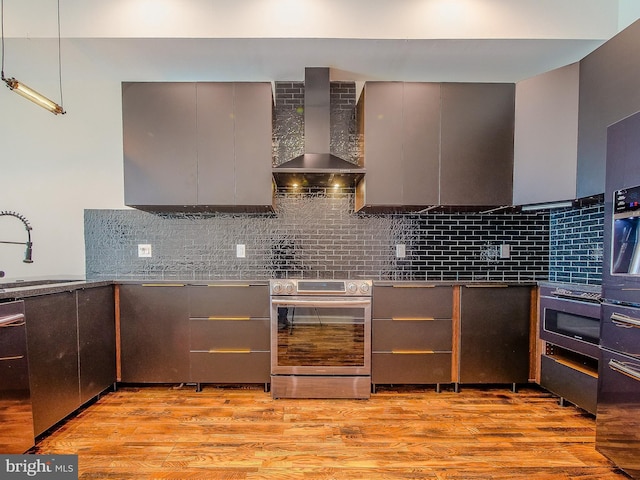 kitchen featuring appliances with stainless steel finishes, gray cabinetry, and wall chimney range hood