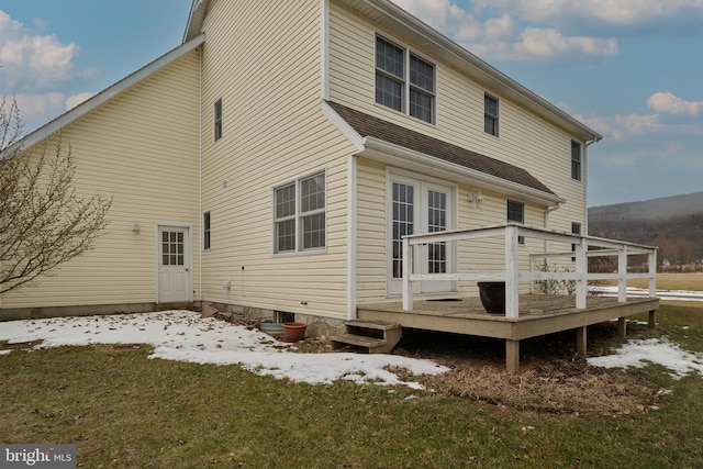 snow covered property featuring a wooden deck, a yard, and french doors