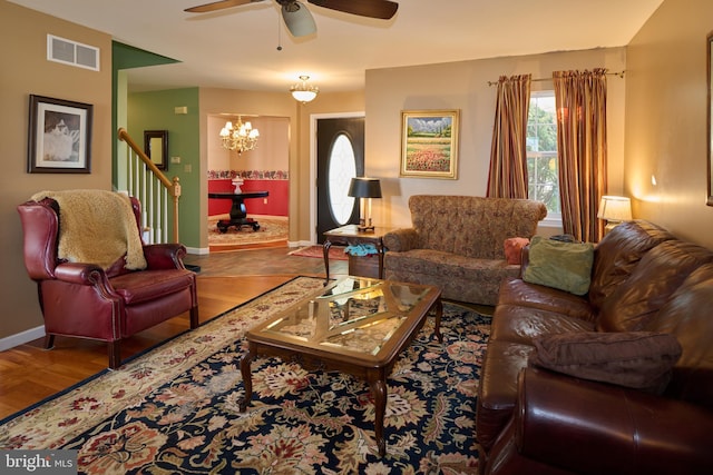 living room with ceiling fan with notable chandelier and hardwood / wood-style floors