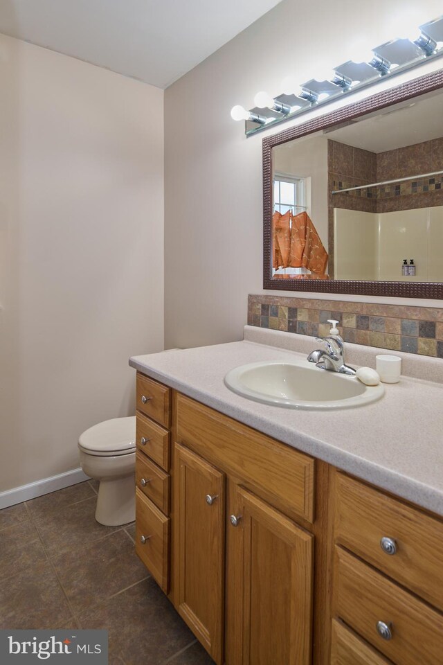 bathroom with tiled shower, vanity, toilet, and tile patterned flooring