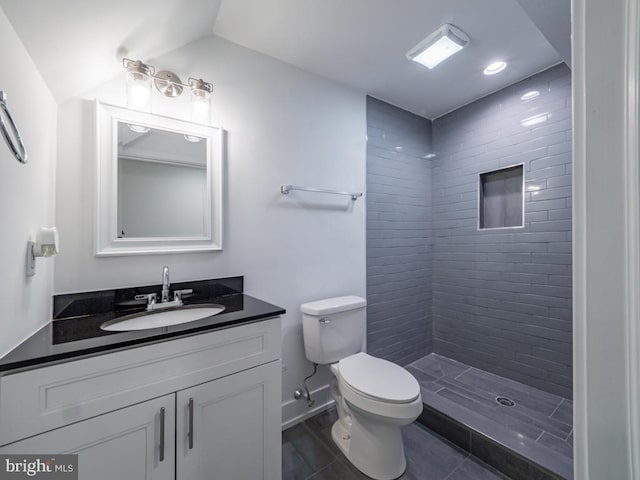 bathroom featuring tiled shower, vanity, and toilet