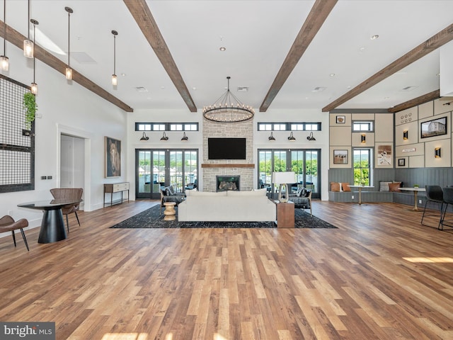 unfurnished living room with hardwood / wood-style flooring, a towering ceiling, a fireplace, and beam ceiling