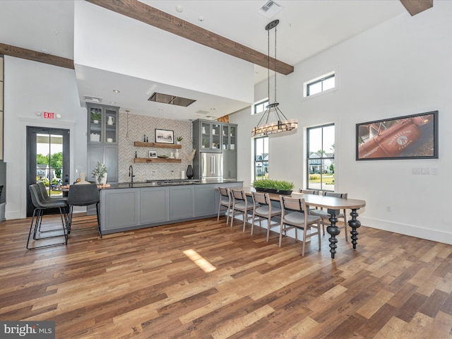 dining space featuring a high ceiling, sink, dark hardwood / wood-style flooring, and beamed ceiling