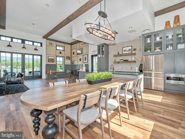 dining room with sink, light hardwood / wood-style floors, french doors, and beamed ceiling