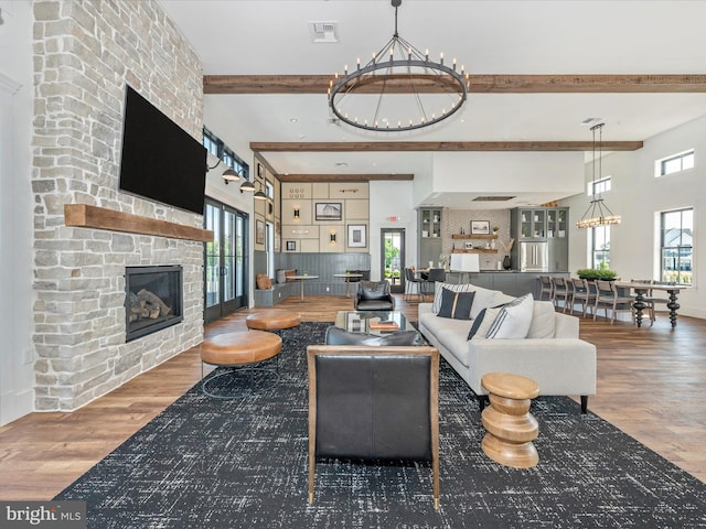 living room with beamed ceiling, a fireplace, dark wood-type flooring, and a notable chandelier