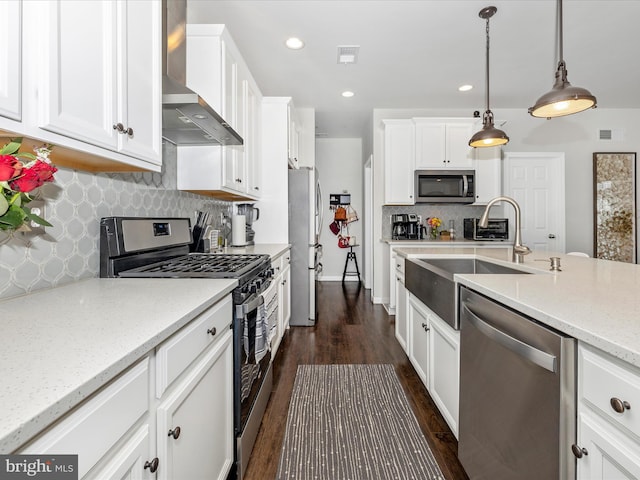 kitchen with hanging light fixtures, appliances with stainless steel finishes, white cabinets, and wall chimney exhaust hood