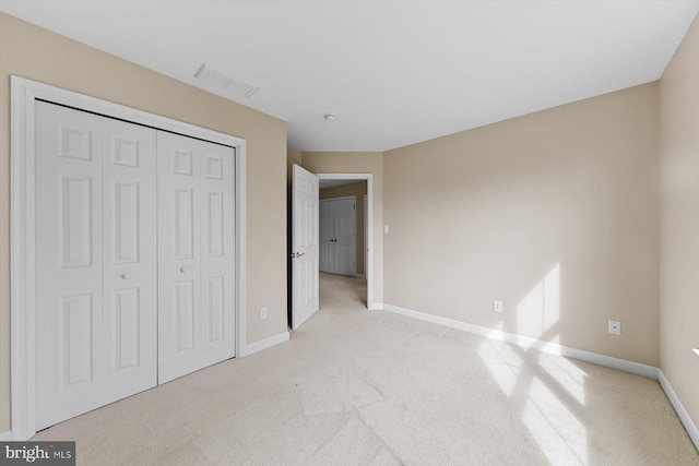 unfurnished bedroom with light colored carpet and a closet