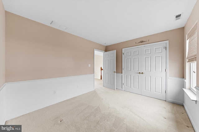 unfurnished bedroom with light carpet and a closet