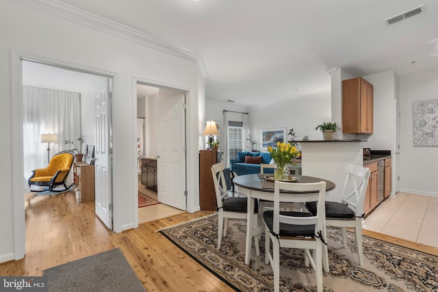 dining area featuring crown molding and light hardwood / wood-style flooring