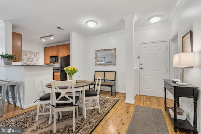 dining room with ornamental molding, rail lighting, and light hardwood / wood-style floors