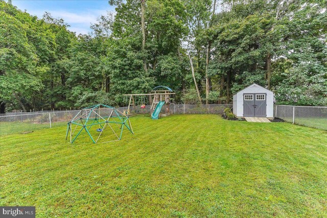 view of yard with an outbuilding, a storage unit, a playground, and a fenced backyard