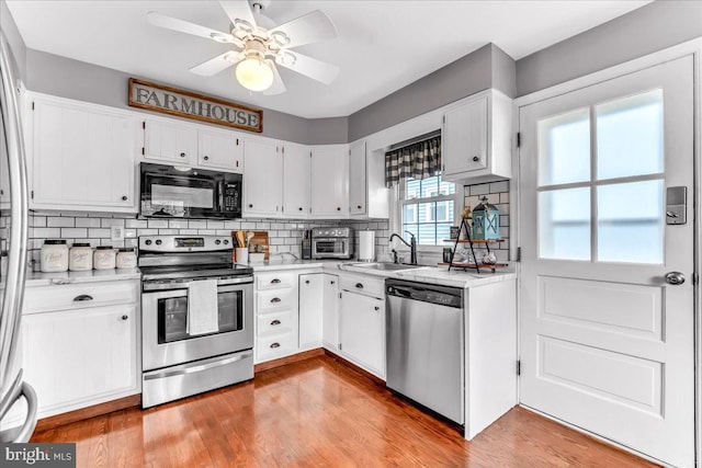 kitchen featuring appliances with stainless steel finishes, light countertops, a sink, and light wood-style flooring