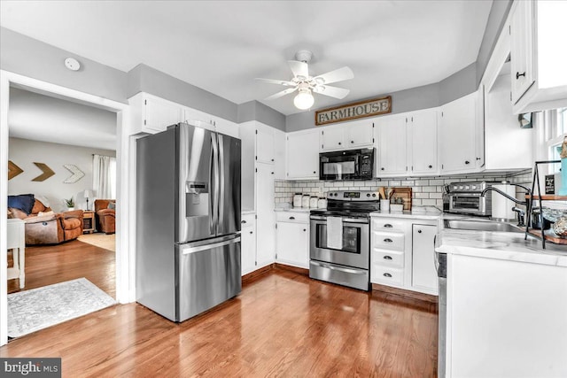 kitchen featuring stainless steel appliances, wood finished floors, a sink, light countertops, and tasteful backsplash