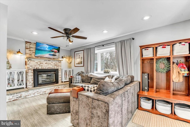 living room with crown molding, a brick fireplace, a ceiling fan, and recessed lighting