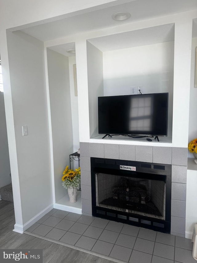 interior details featuring a tiled fireplace and baseboards