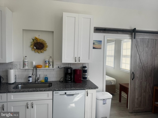 kitchen featuring backsplash, white dishwasher, a sink, and white cabinetry