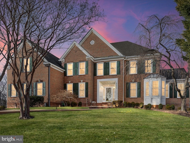 view of front of home with a yard and brick siding