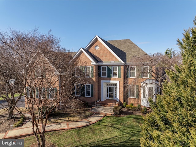 view of front facade with brick siding and a front yard