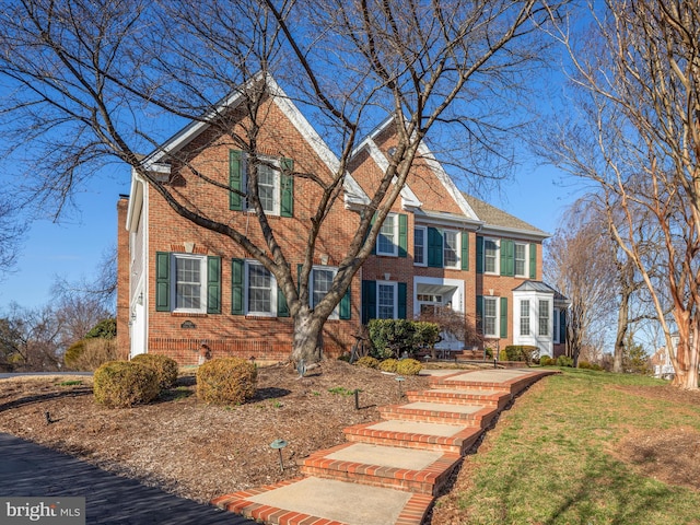 view of front of house with a front yard, brick siding, and a chimney