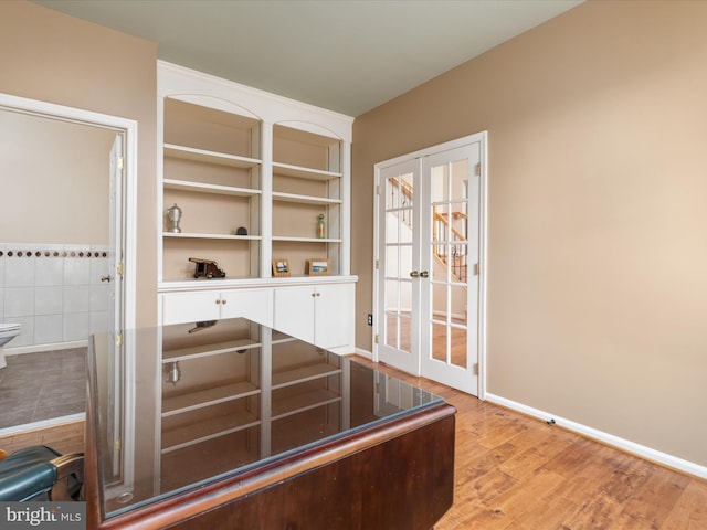 interior space with wood finished floors, baseboards, and french doors