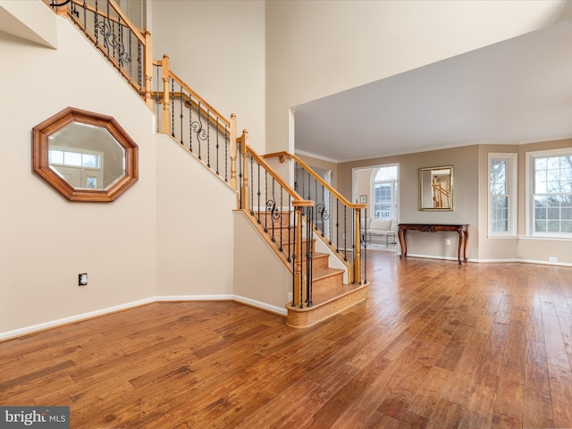 interior space featuring hardwood / wood-style floors, stairs, baseboards, and a towering ceiling