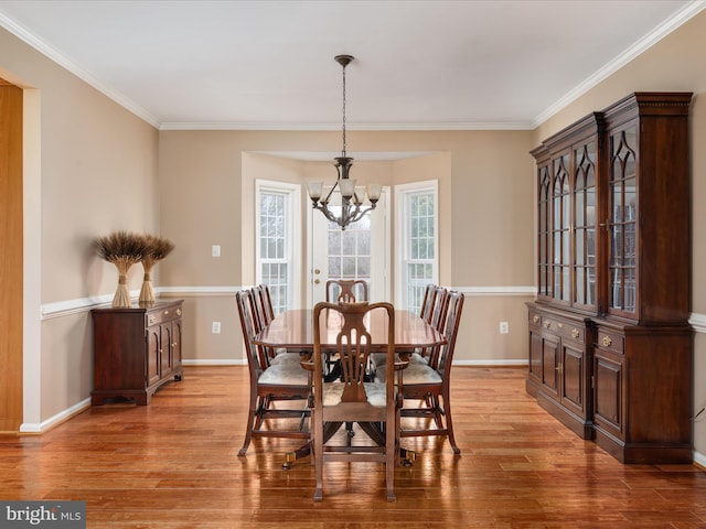 dining space with baseboards, an inviting chandelier, and light wood-style flooring