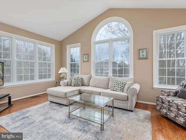 living room with vaulted ceiling, plenty of natural light, wood finished floors, and visible vents