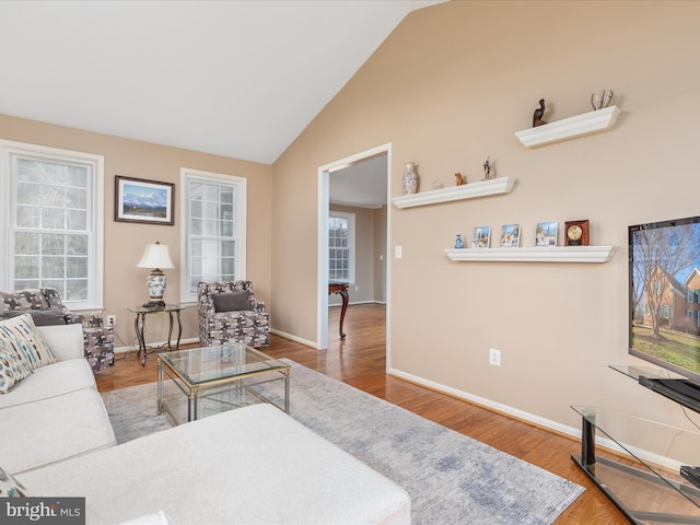 living room with baseboards, high vaulted ceiling, and wood finished floors