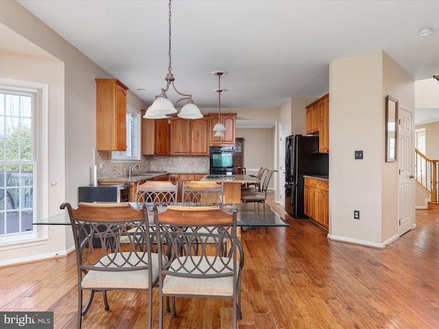 dining area with baseboards, stairs, and light wood finished floors