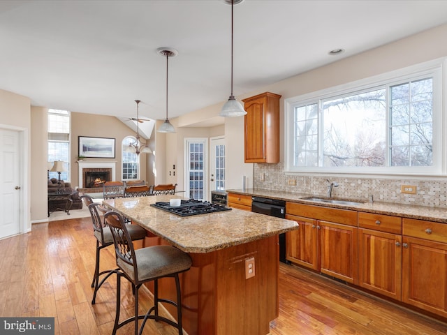 kitchen featuring black appliances, a sink, a center island, a fireplace, and decorative backsplash