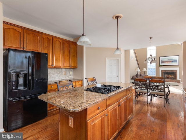 kitchen featuring light stone counters, decorative backsplash, dark wood finished floors, and black appliances