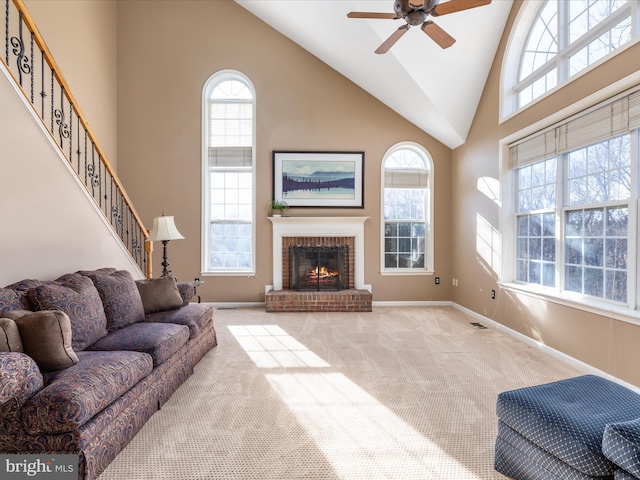 living area featuring baseboards, carpet, stairs, a fireplace, and high vaulted ceiling