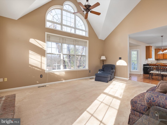 carpeted living room with visible vents, baseboards, high vaulted ceiling, and ceiling fan