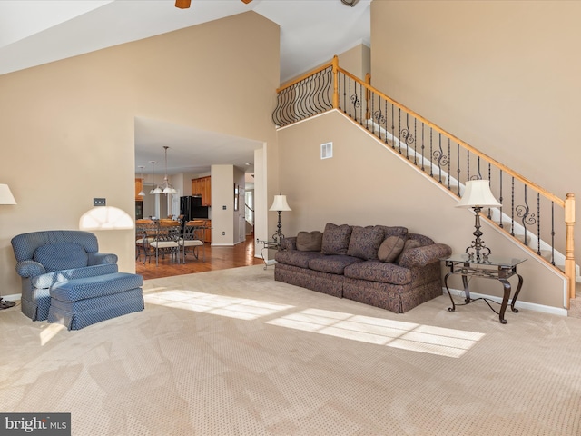 living room featuring visible vents, baseboards, carpet, stairs, and high vaulted ceiling