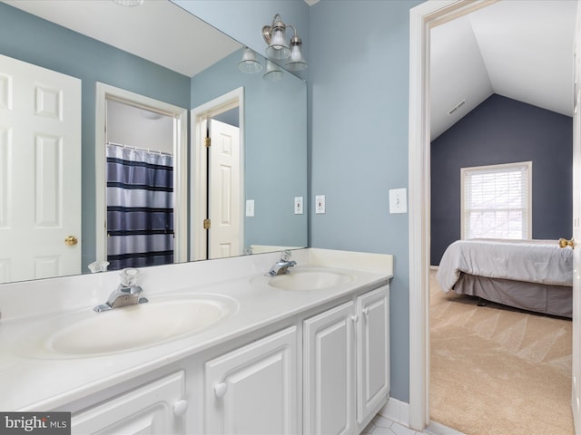 ensuite bathroom featuring double vanity, vaulted ceiling, connected bathroom, and a sink