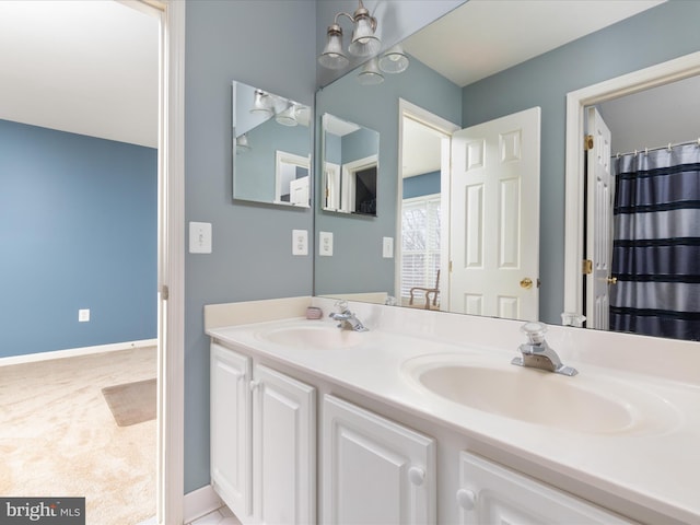 full bath featuring double vanity, a chandelier, baseboards, and a sink