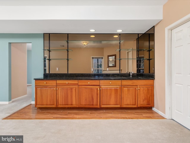 bathroom with wood finish floors, a sink, carpet flooring, double vanity, and baseboards