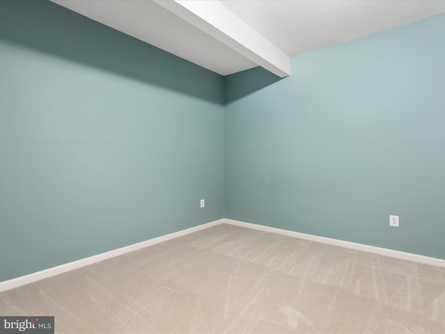 carpeted empty room with beamed ceiling and baseboards