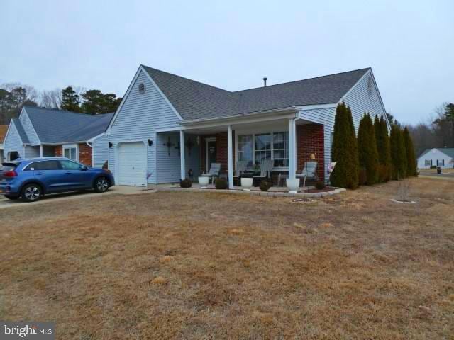 view of front of home with a garage, a front lawn, and a porch