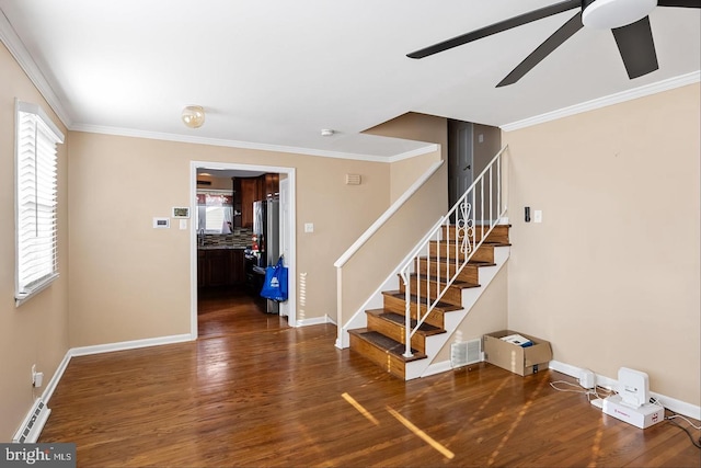 stairs with a wealth of natural light, ornamental molding, and wood-type flooring