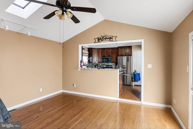 unfurnished living room featuring ceiling fan, light hardwood / wood-style flooring, and vaulted ceiling with skylight