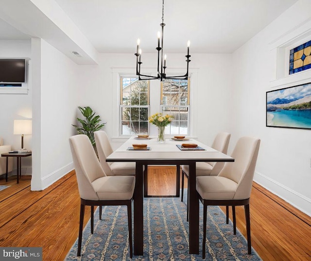 dining area featuring hardwood / wood-style floors and an inviting chandelier