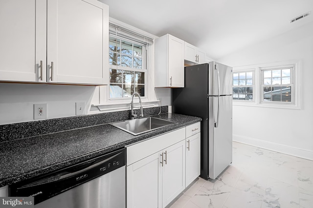 kitchen featuring lofted ceiling, appliances with stainless steel finishes, sink, and white cabinets