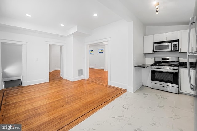 kitchen with lofted ceiling, stainless steel appliances, and white cabinets