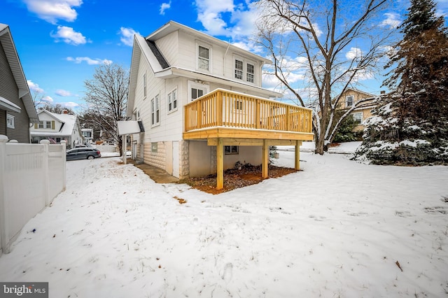 snow covered rear of property with a deck