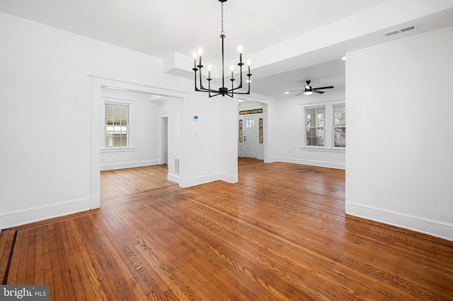 unfurnished dining area with hardwood / wood-style flooring, a healthy amount of sunlight, and ceiling fan with notable chandelier