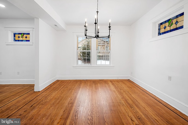 unfurnished dining area with an inviting chandelier and wood-type flooring